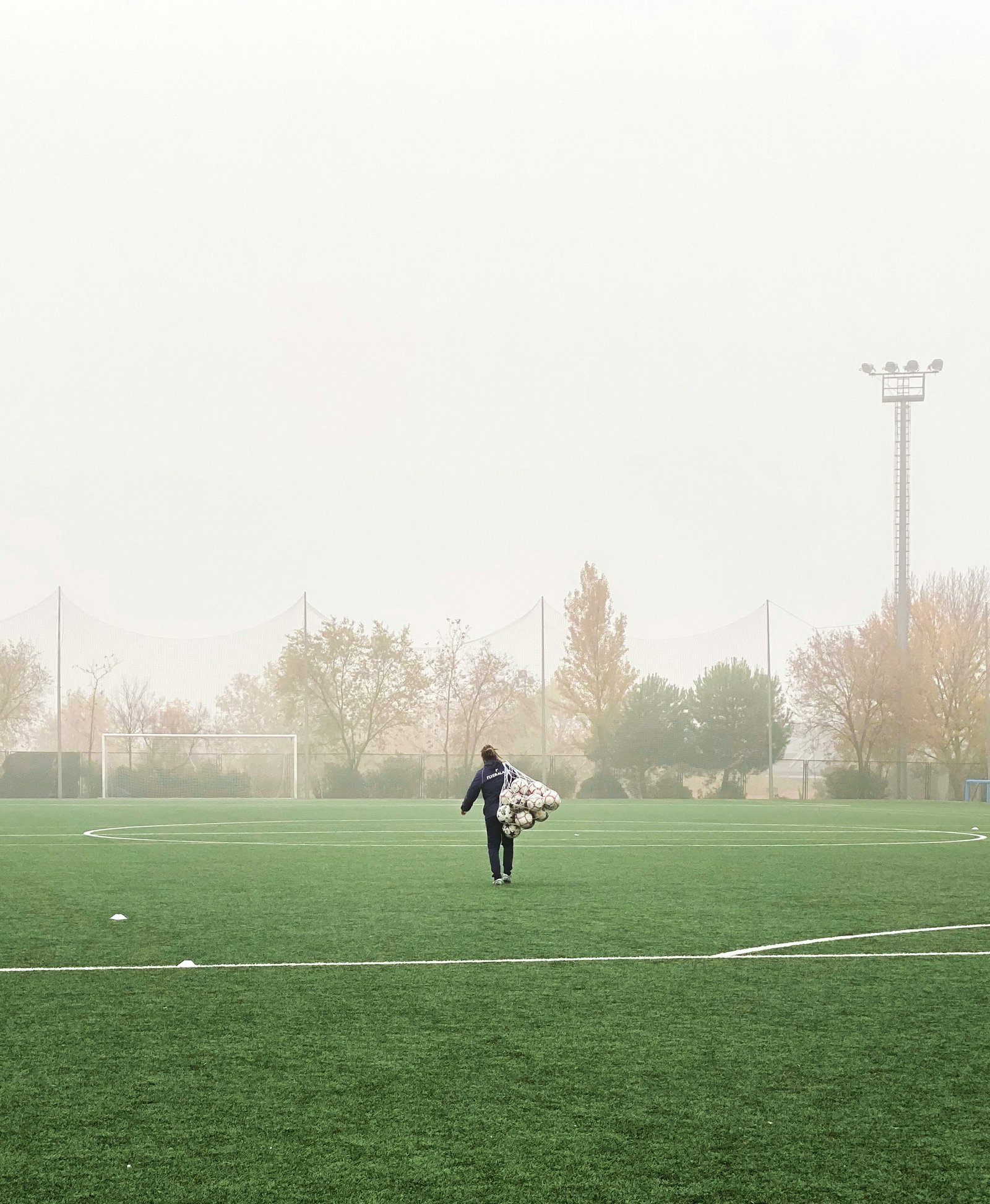 Coach portant un filet de ballons sur un terrain